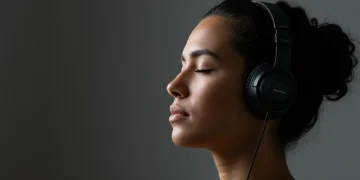 Person practicing mindful listening with headphones in a peaceful setting