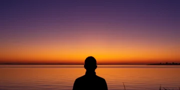 Person looking at sunrise, symbolizing self-discipline and new beginnings for personal growth.