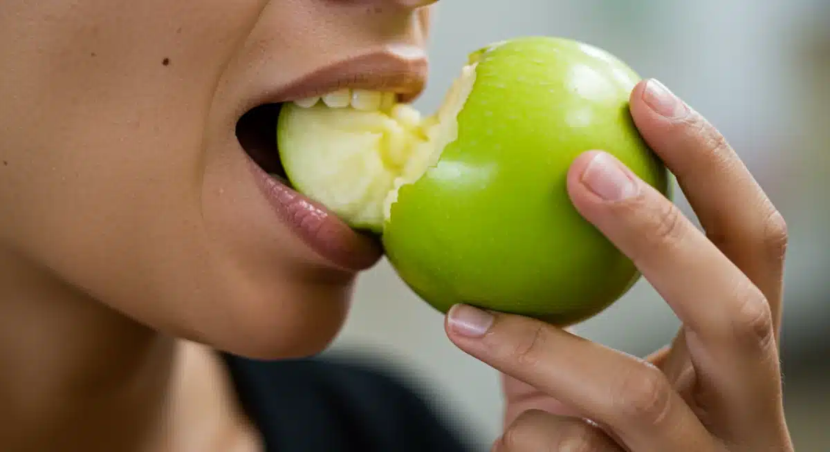 Person mindfully biting a green apple